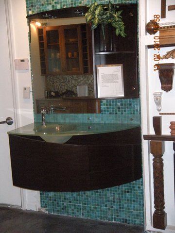 Small bathroom sink with turquoise mosaic tile and a mirror above it.