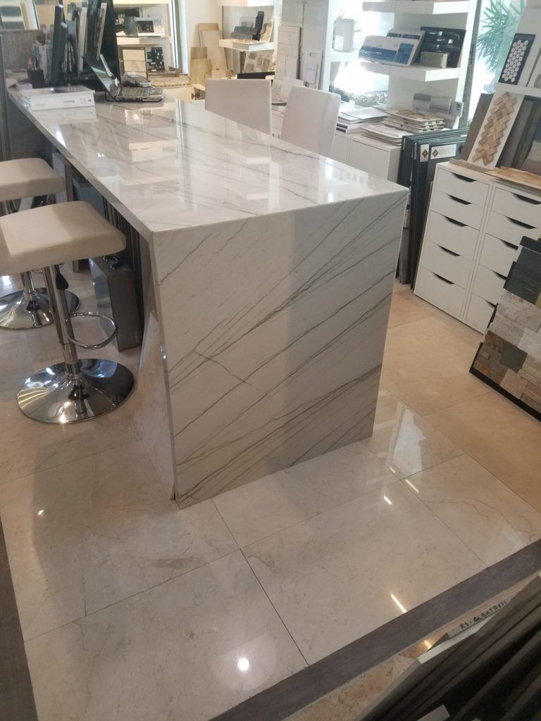 Modern kitchen with a glossy white island and marble-look floor in a showroom setting