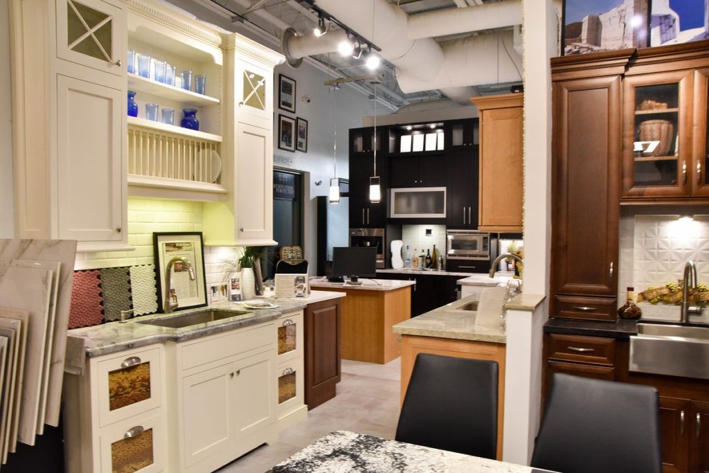 Bright showroom kitchen with white cabinetry, dark wood cabinets, and marble countertops