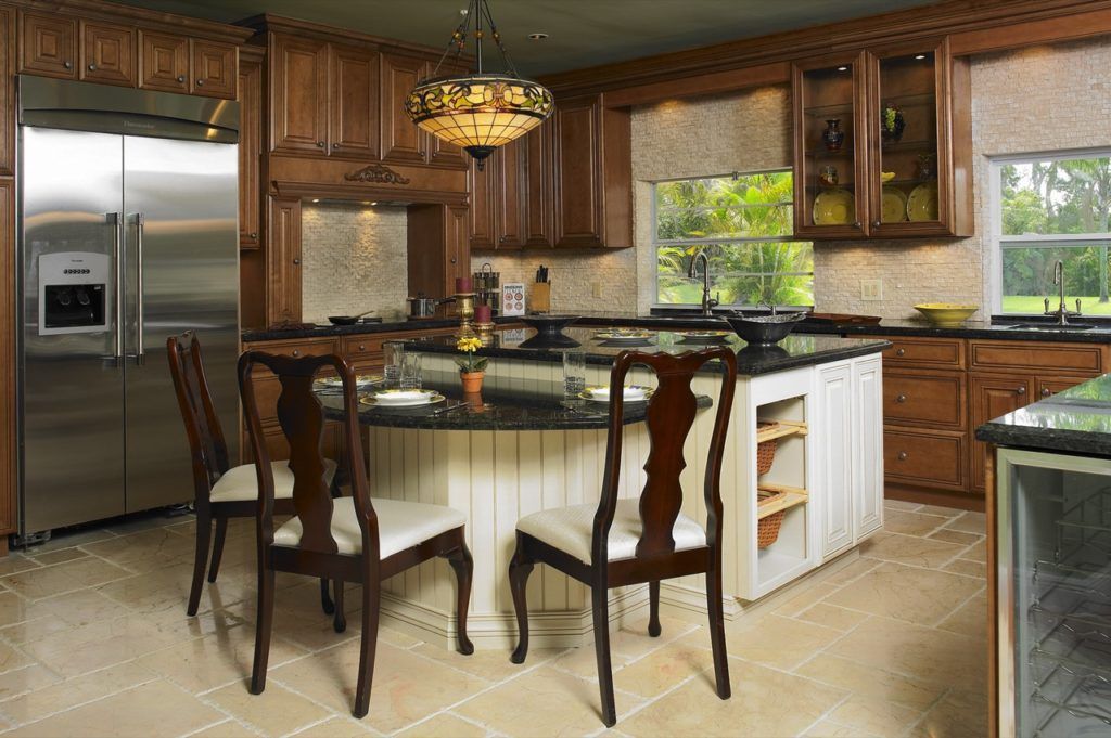 Wooden kitchen with island, bar stools, stainless fridge, and large windows letting in daylight