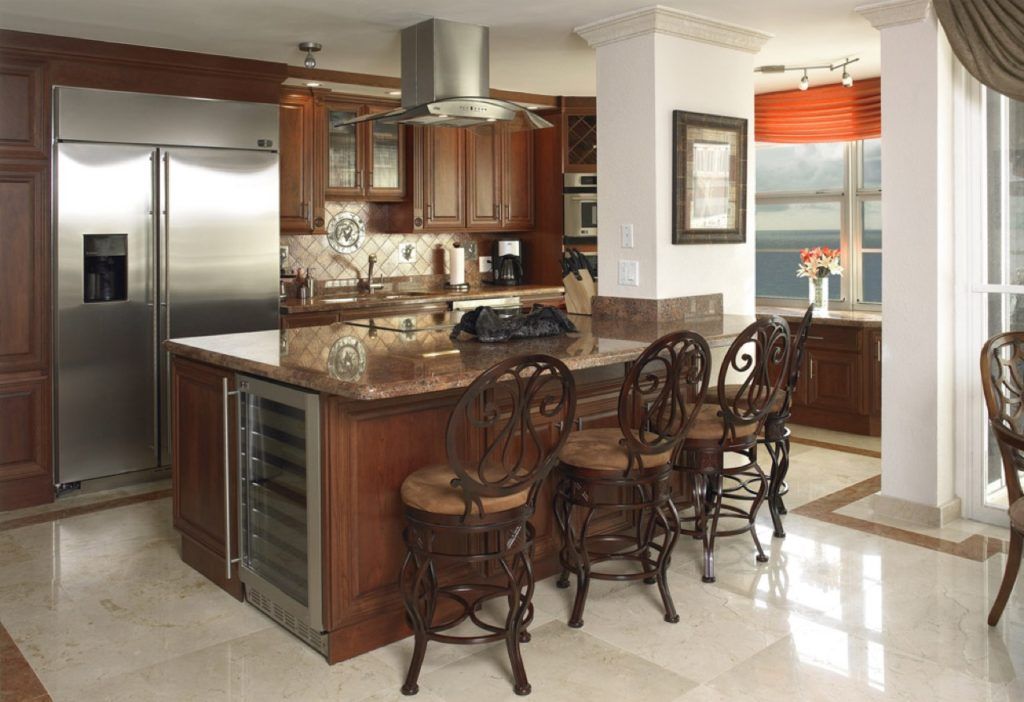 Modern kitchen with stainless steel fridge, wood cabinets, granite island, and bar stools