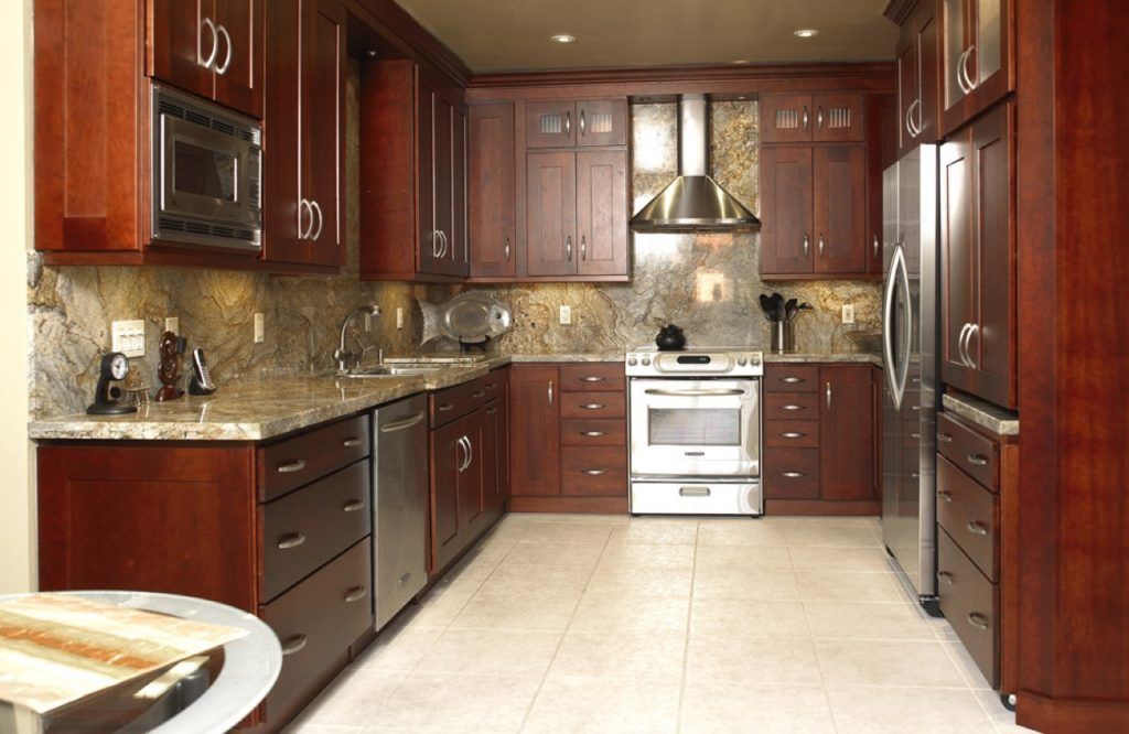 Modern kitchen with dark wood cabinets, granite countertops, tiled backsplash, and white stove under a range hood