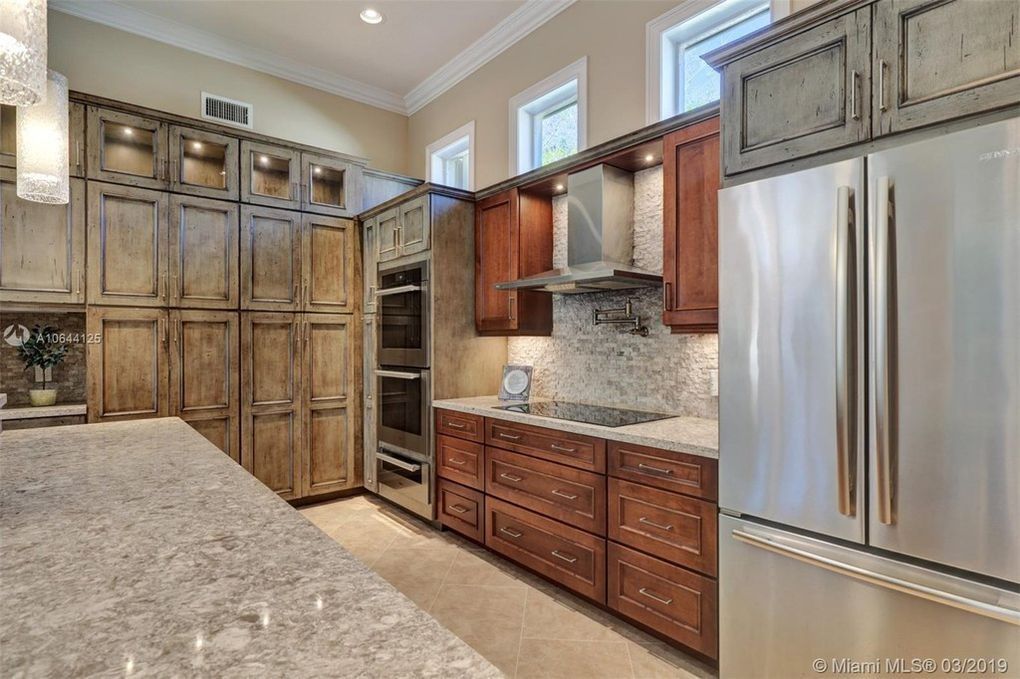 Spacious kitchen with wood cabinets, granite counters, and stainless steel refrigerator and range hood.