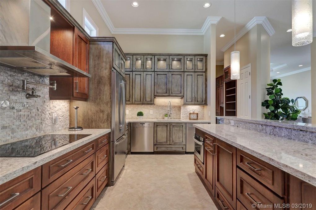 Bright modern kitchen with wood cabinets, granite countertops, stainless steel appliances, and a central island
