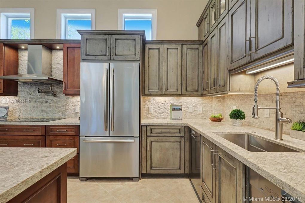 Modern kitchen with stainless steel refrigerator, gray cabinets, granite counters, and large sink