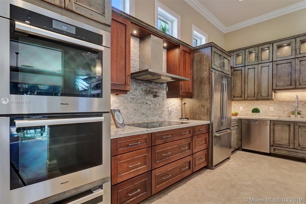 Modern kitchen with stainless steel appliances, wood cabinets, granite counters, and built-in oven and fridge