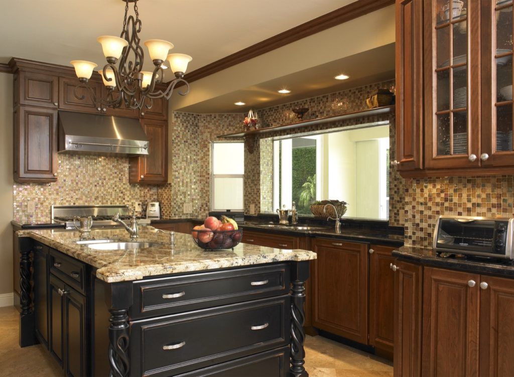 Elegant kitchen with granite island, dark wood cabinets, mosaic backsplash, and chandelier lighting