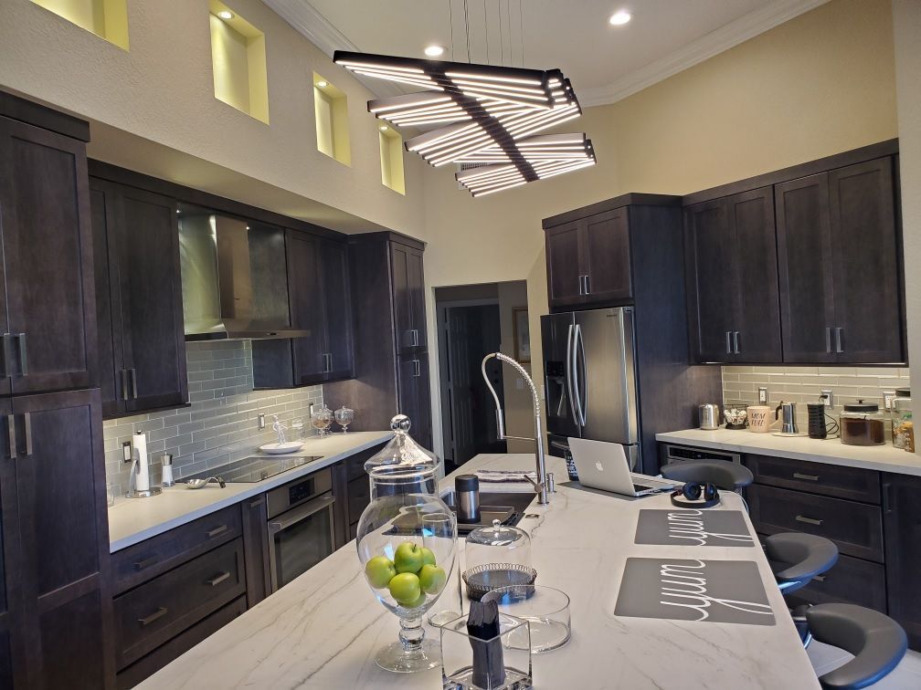 Modern kitchen with dark cabinets, white island, pendant lights, and countertop decor