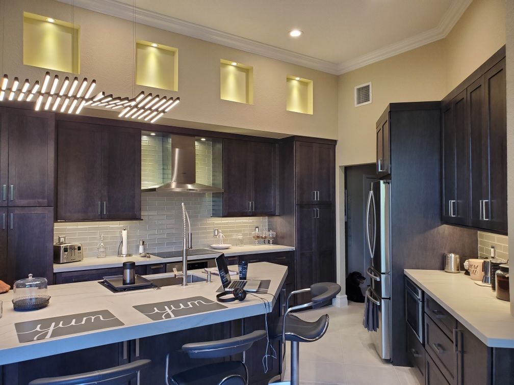 Modern kitchen with dark cabinets, light countertops, island, and stainless steel appliances