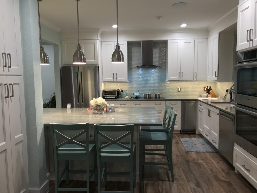 Modern kitchen with white cabinets, stainless appliances, island seating, and pendant lights