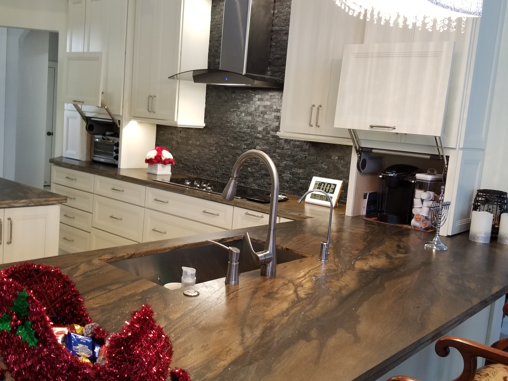 Kitchen with a large wood island, stainless sink, white cabinets, and red holiday decor