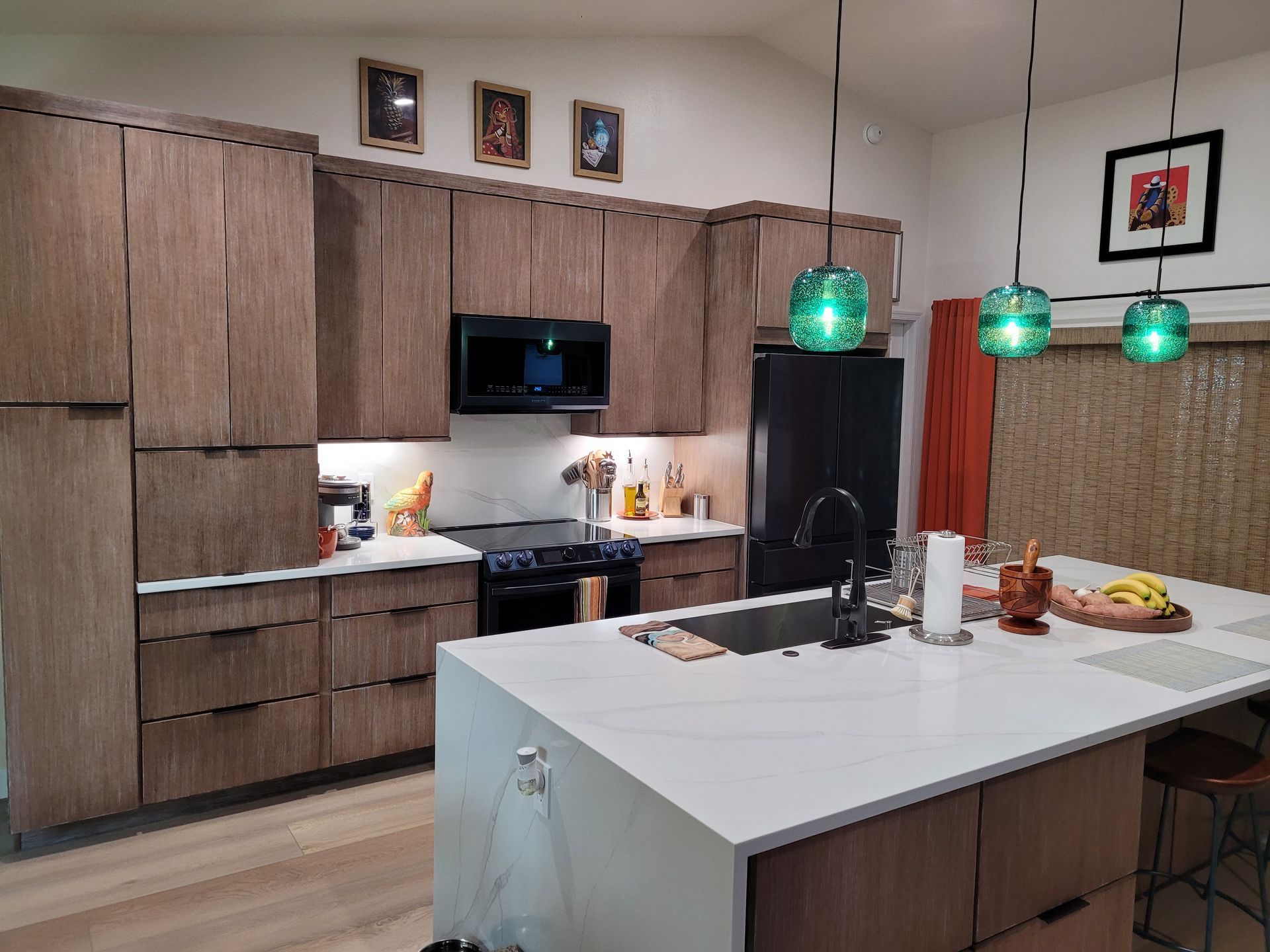 Modern kitchen with wood cabinets, white island, and green pendant lights