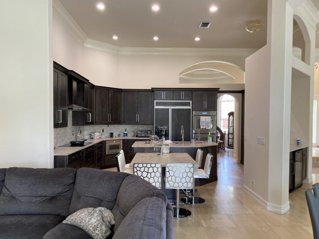 Modern open-concept kitchen and living room with dark cabinets, island seating, and a gray sofa