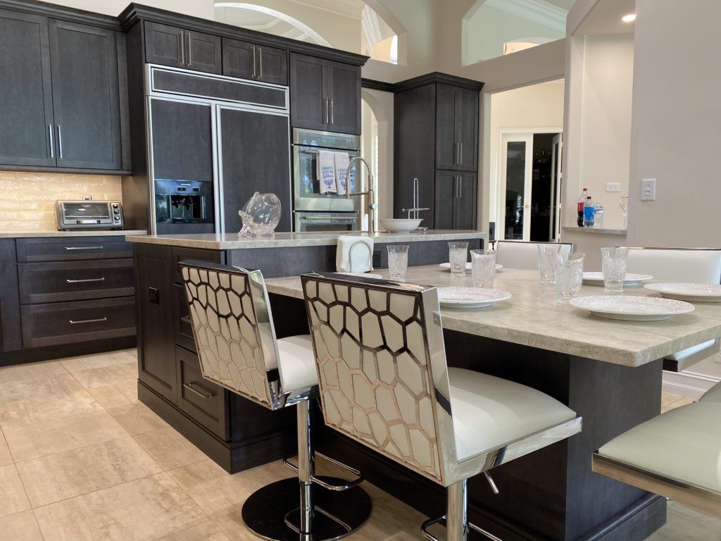 Modern kitchen with dark cabinets, large island, and patterned barstools under pendant lights
