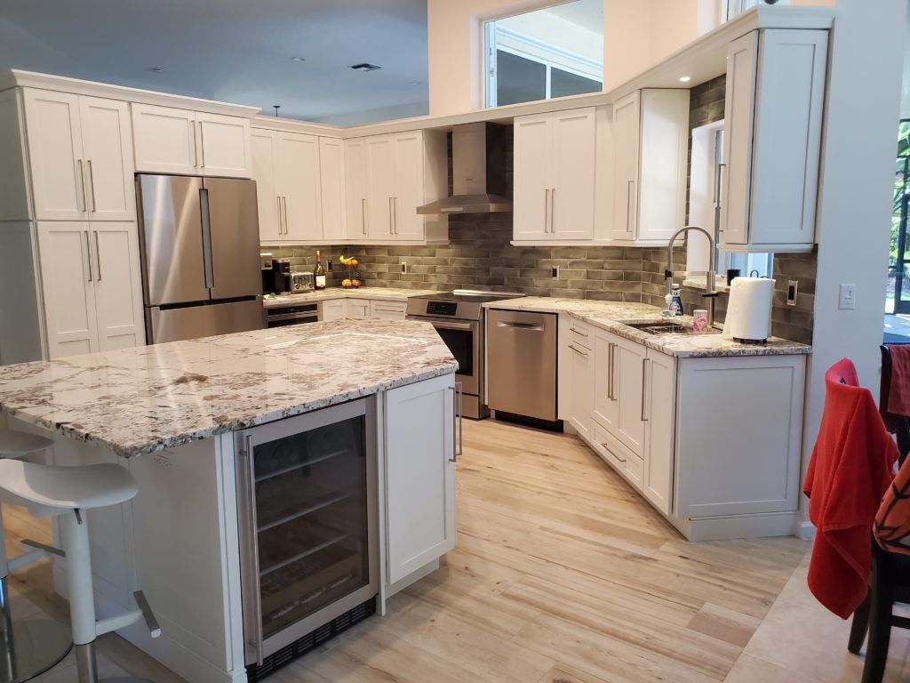 Bright modern kitchen with white cabinets, granite island, stainless steel appliances, and light wood floors
