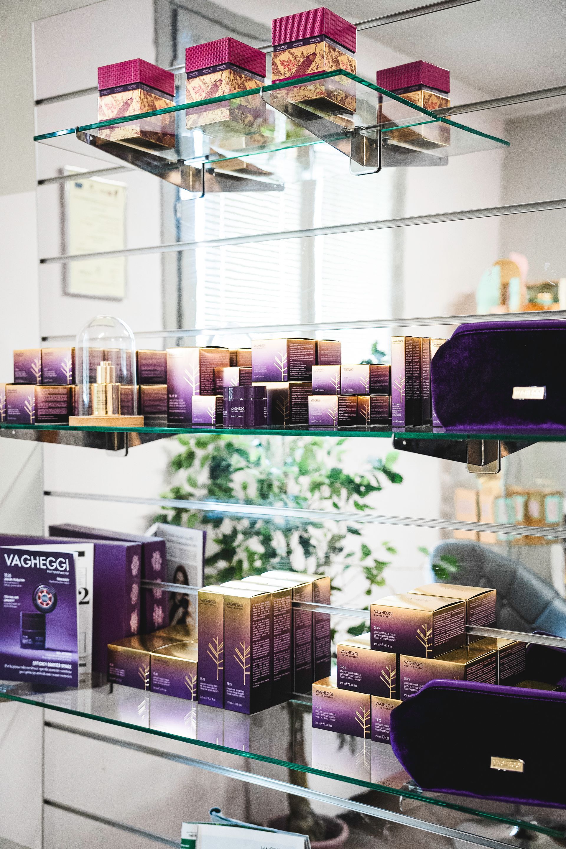 In un negozio ben illuminato, sugli scaffali sono esposti i prodotti per la cura della pelle di colore viola del marchio Vagheggi.