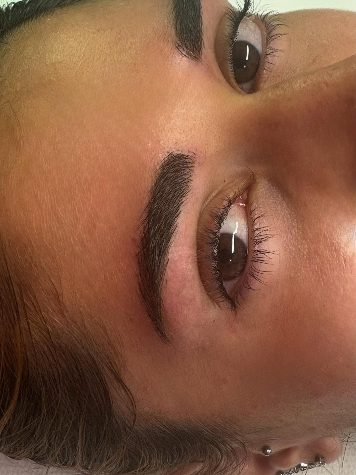 Primo piano del sopracciglio di una persona dopo una procedura di microblading o tatuaggio, che mostra un pigmento scuro e ben definito.