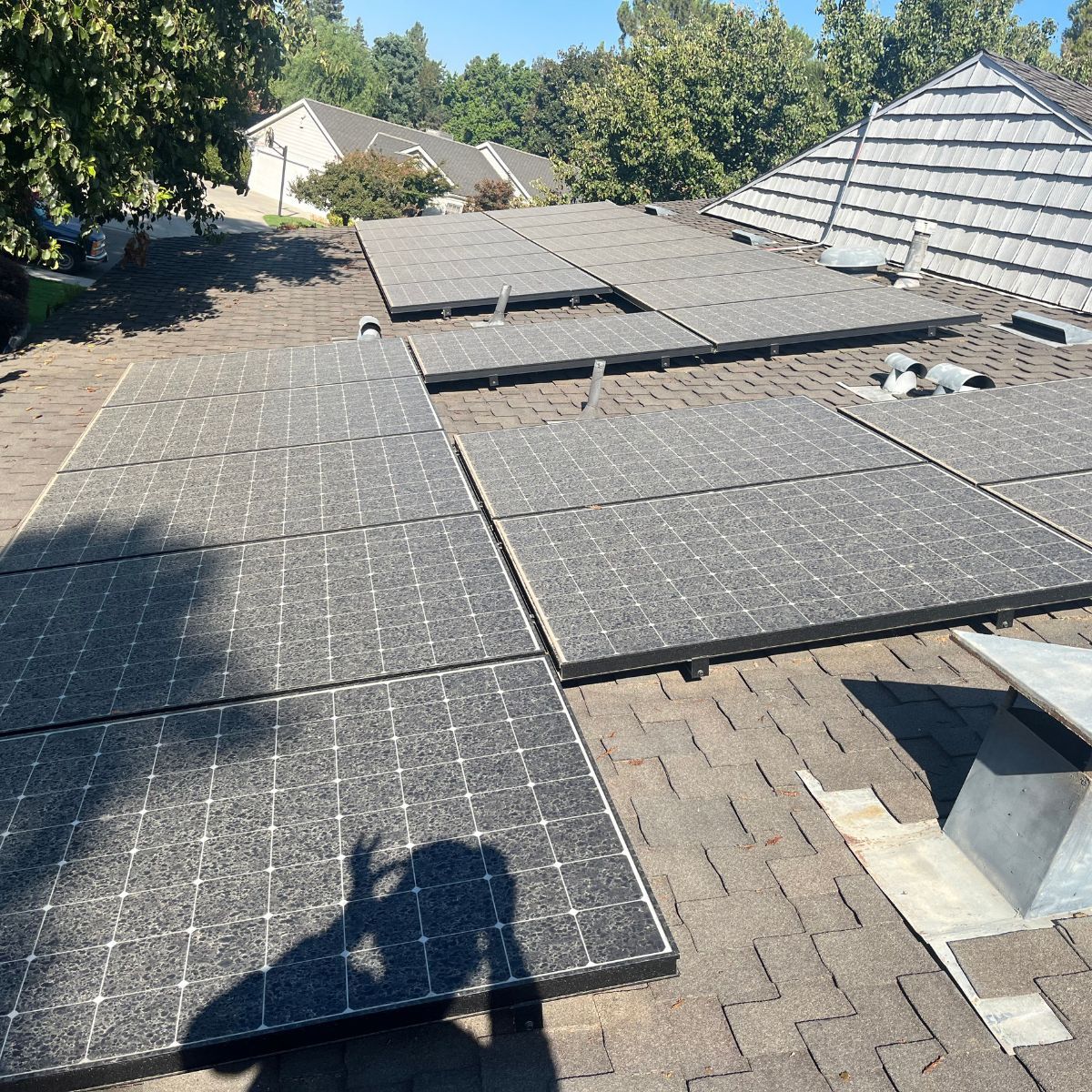 Roof under repair with black underlayment sheets and exposed shingles on a sunny day