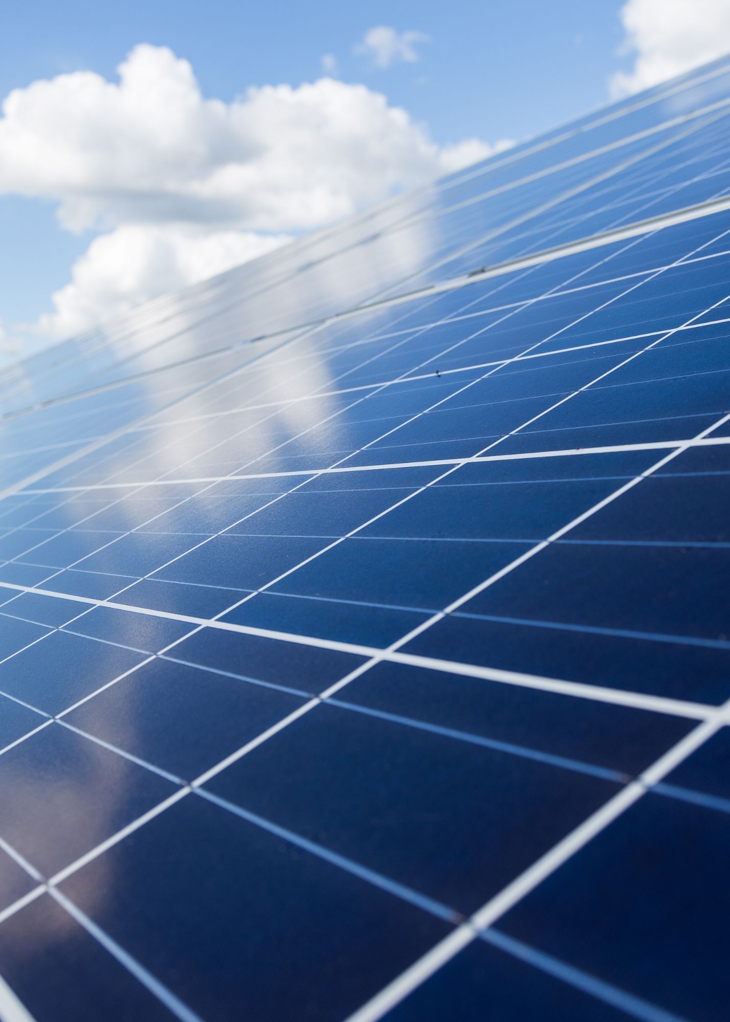 Solar panels against a blue sky with clouds, harvesting sunlight.