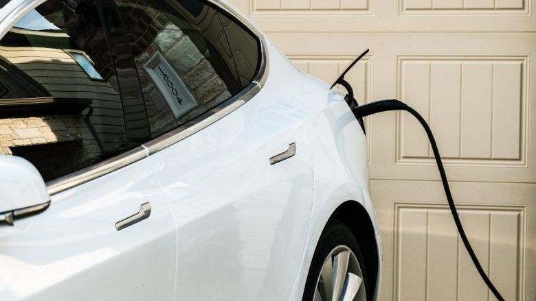 White electric car plugged into a charging station in a garage