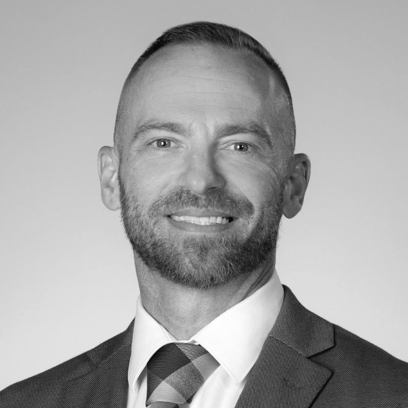 Man in a suit smiles at the camera, short hair, and a trimmed beard.