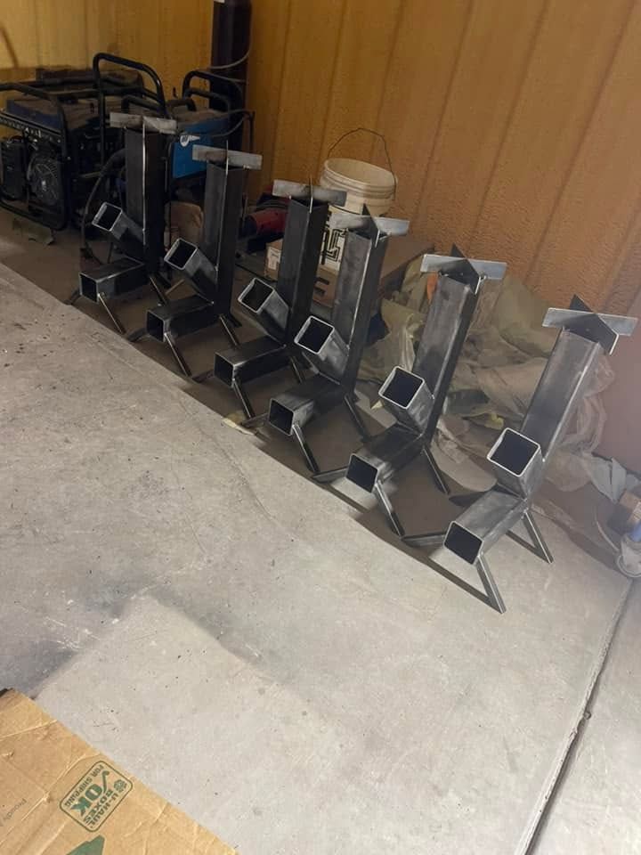 Line of metal jacks or supports leaning against a wooden wall in a garage-like space.