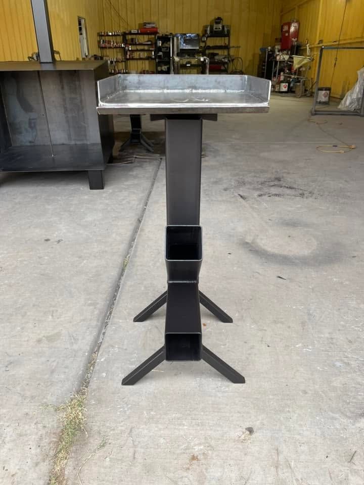Black metal pedestal stand with a rectangular top in a workshop garage.