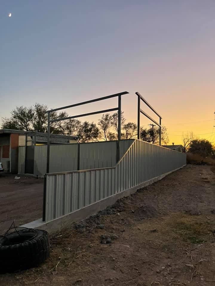 Outdoor metal walkway ramp with railings beside a building at sunset.