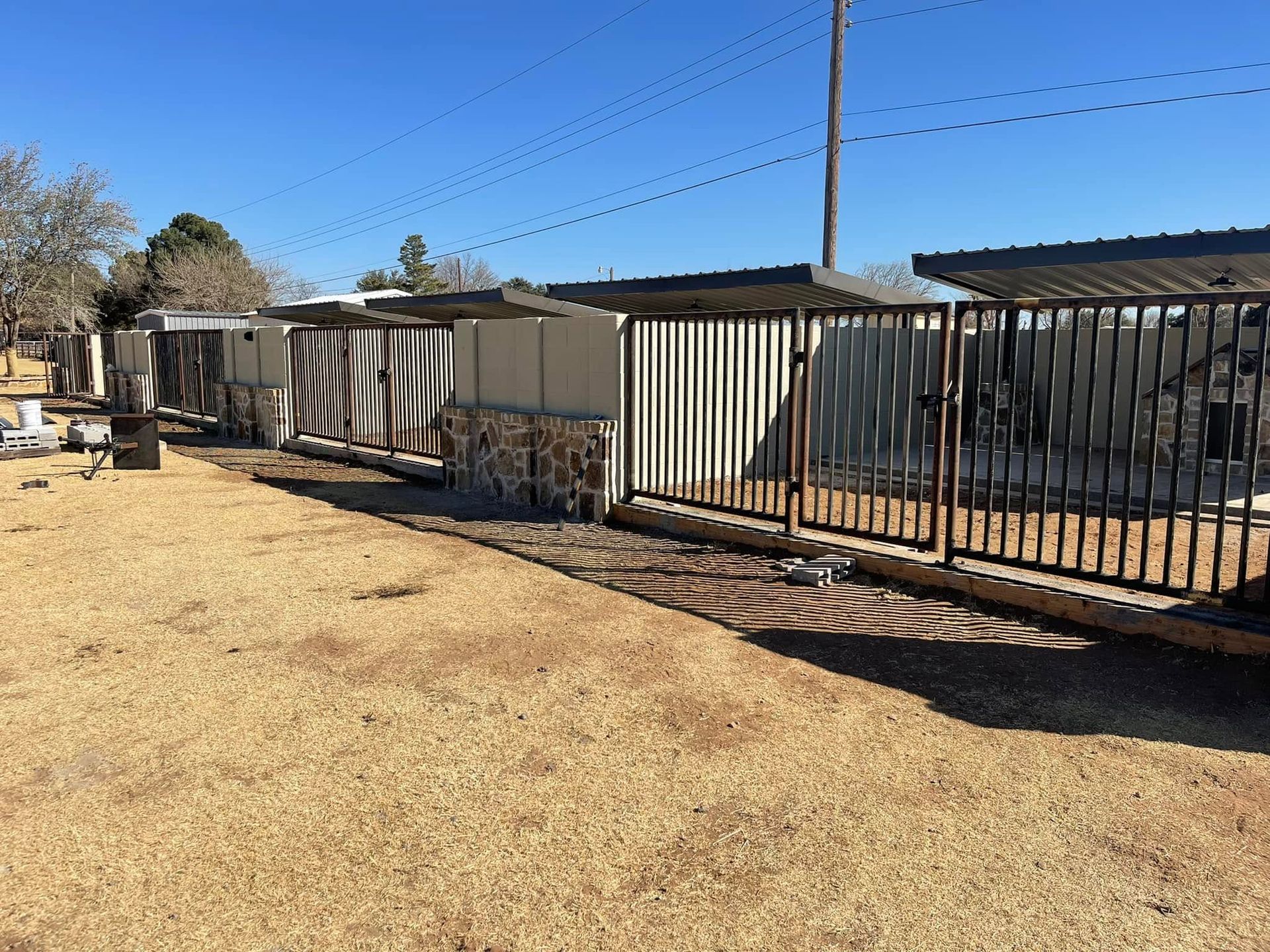 Single-story beige homes with a fenced yard under a clear blue sky