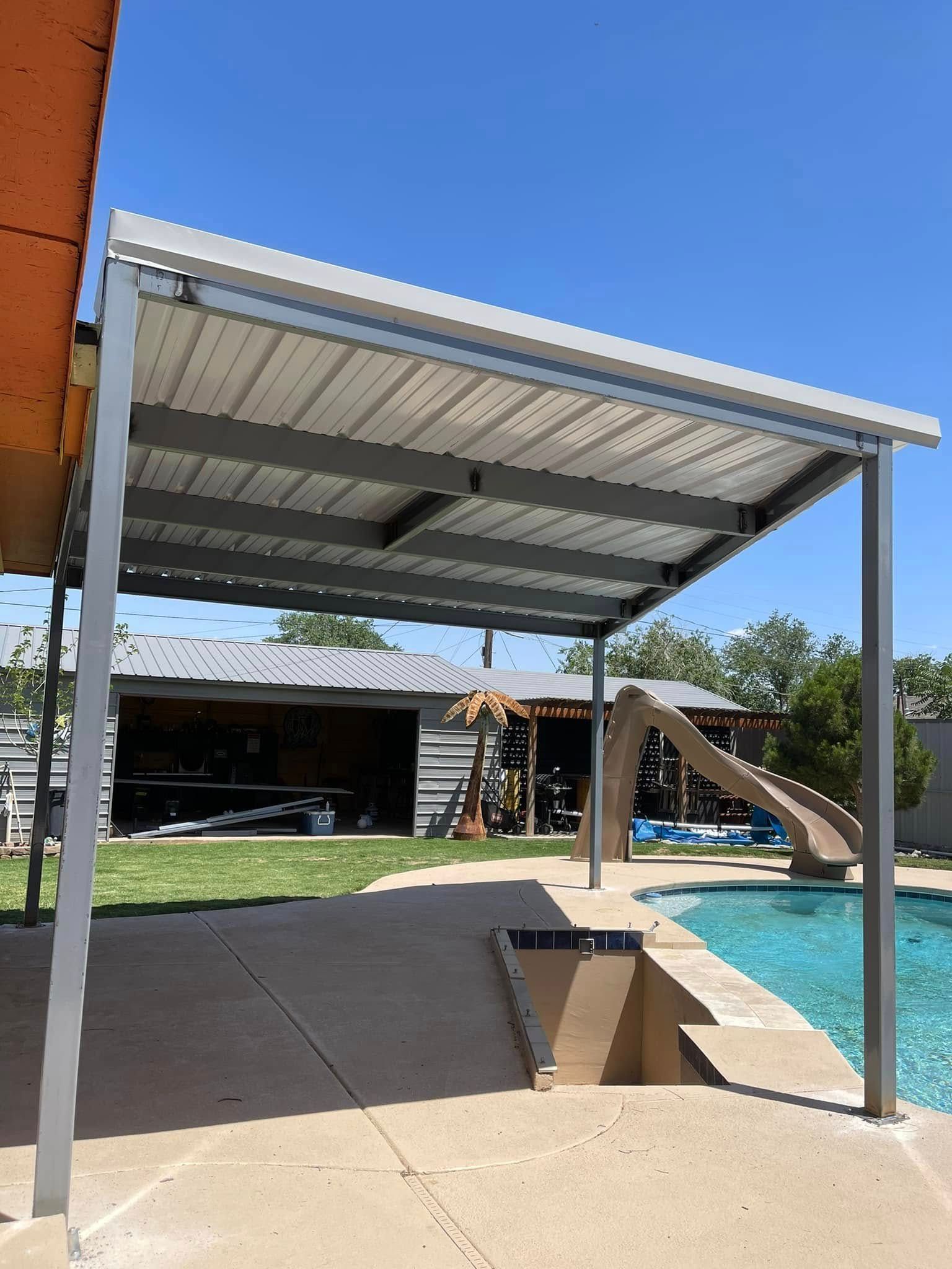 Poolside shaded patio with metal roof beside a swimming pool and backyard lawn