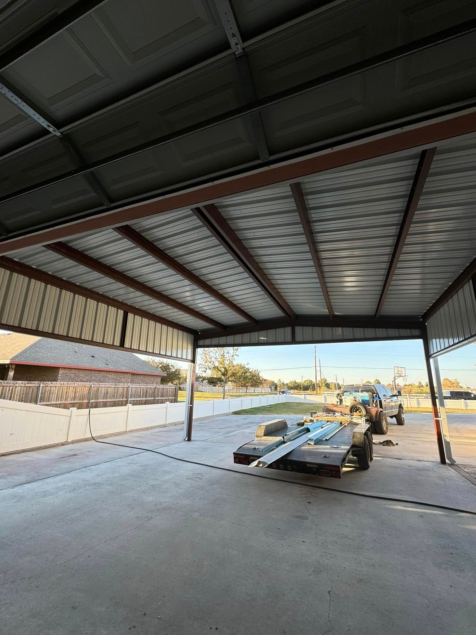 Open-sided metal shed with a small boat on a trailer in an empty concrete yard