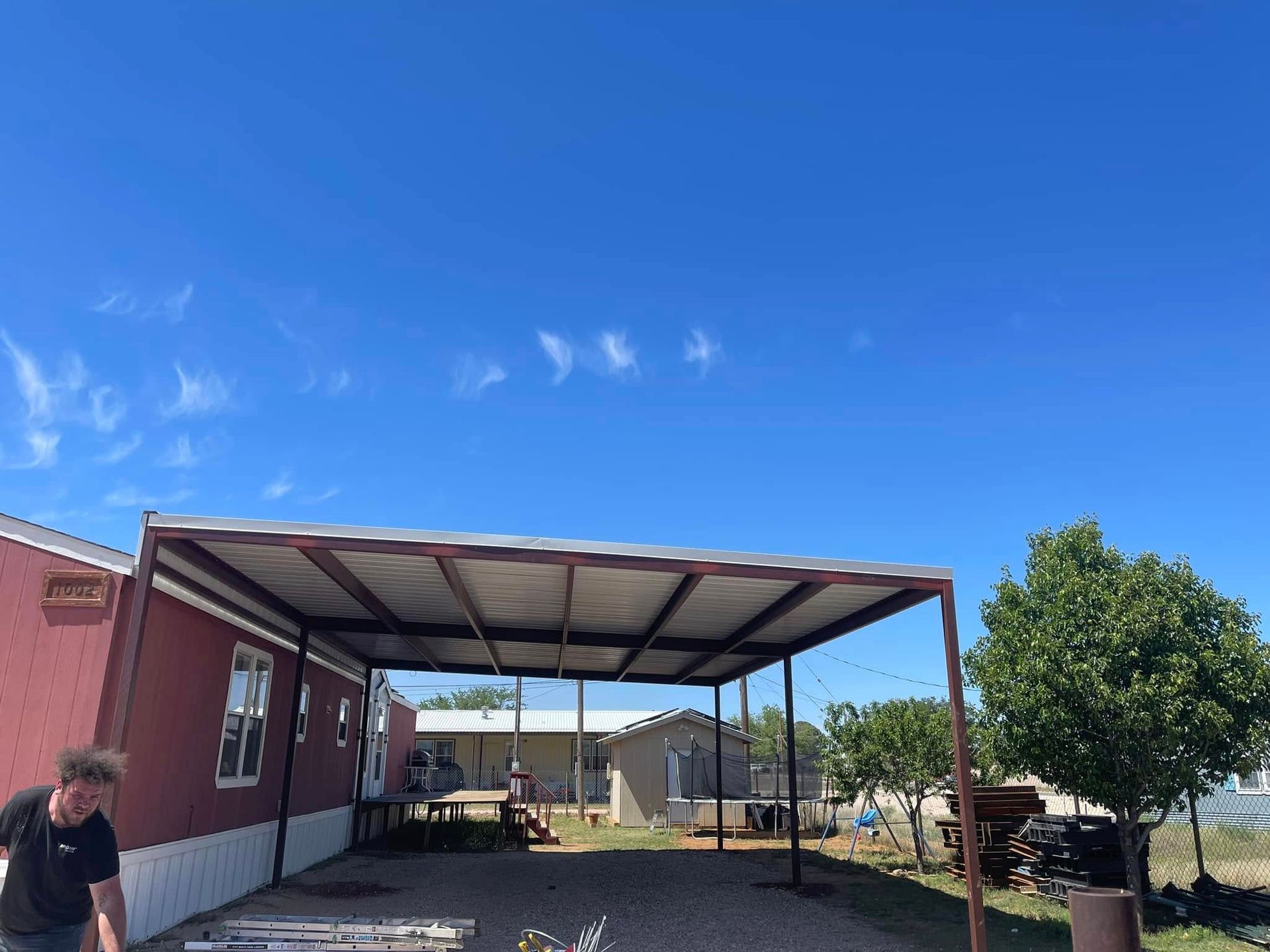 Covered patio beside a pink house with a blue sky and a person standing at left.