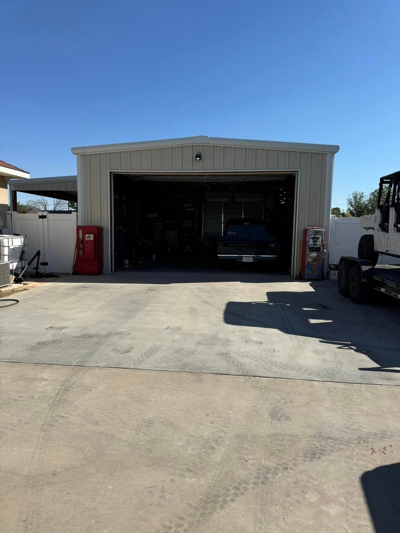 Open garage bay with a car inside, concrete driveway, and clear blue sky