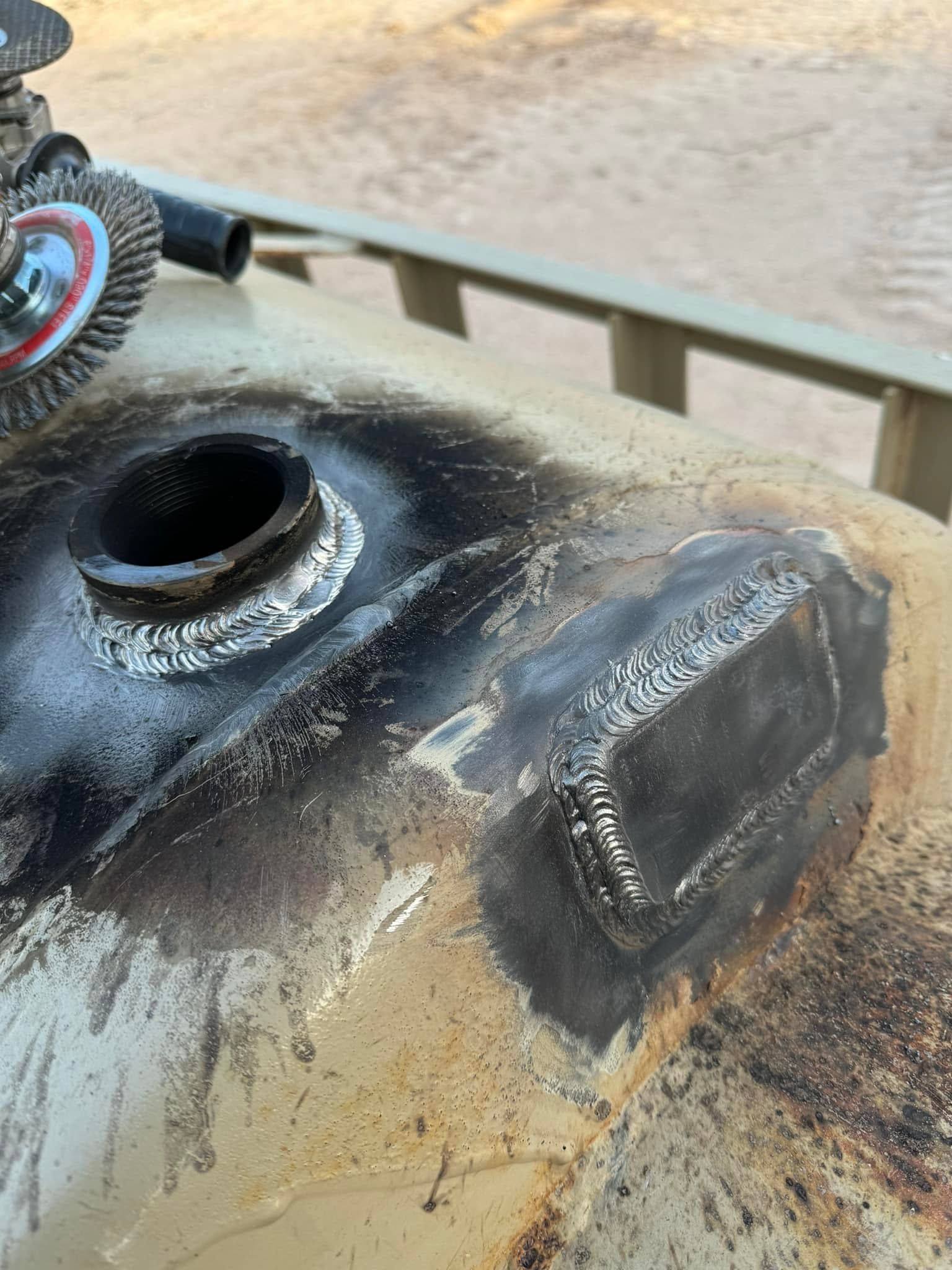 Charred metal tank with open filler hole and burned blackened top outdoors
