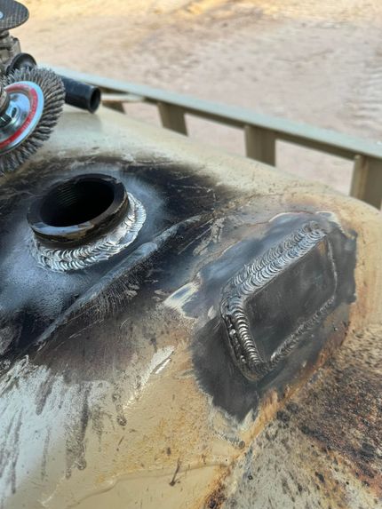 Charred metal tank with open filler hole and burned blackened top outdoors
