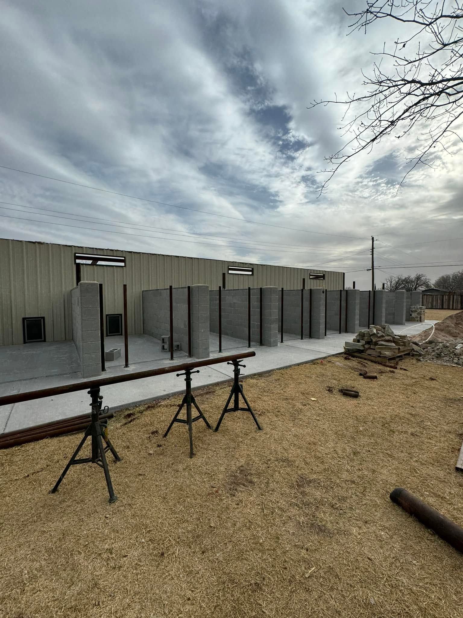 Outdoor concrete building under a cloudy sky with black metal railings and gravel foreground.