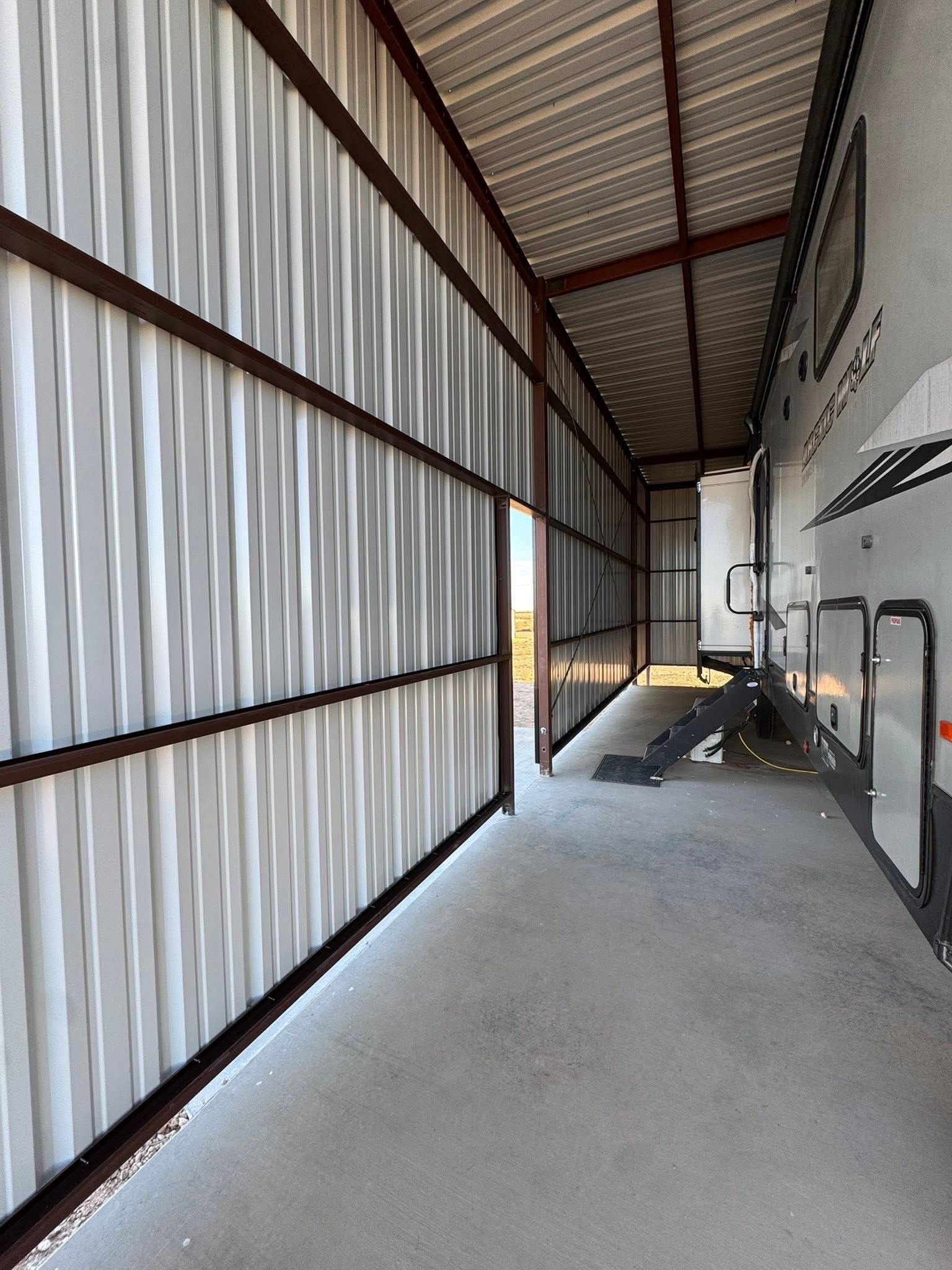 Empty industrial corridor with corrugated metal walls, concrete floor, and a ramp at the far end