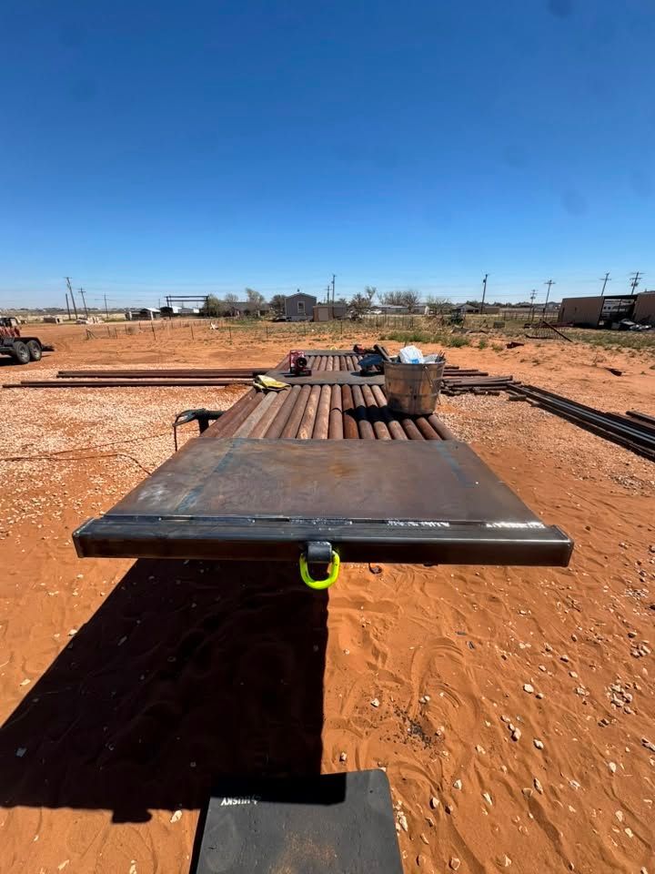 Long wooden platform on red dirt in a wide open field under a clear blue sky.