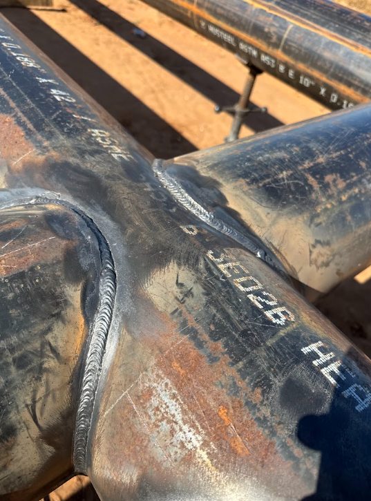Close-up of rusted steel pipes and welded joints on a construction site.