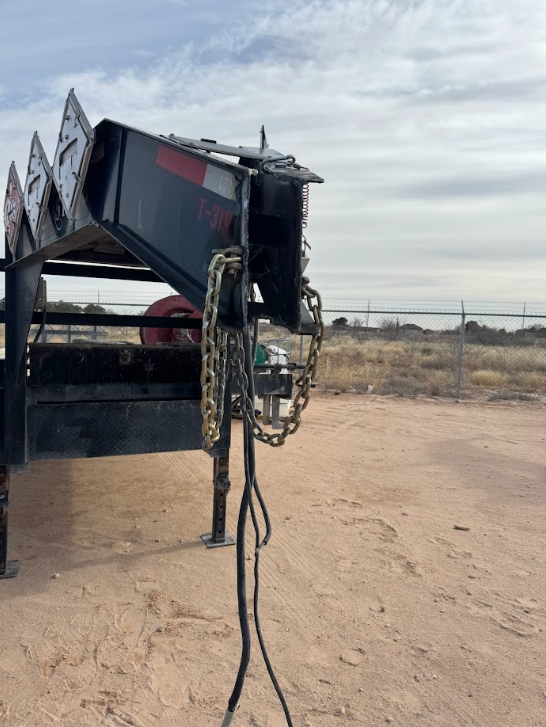 Trailer hitch with hanging cables on a sandy desert roadside under a cloudy sky