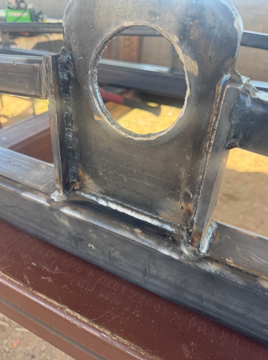Close-up of a welded metal bracket with a circular hole on a workbench