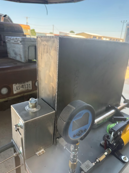 Industrial equipment with a pressure gauge and metal tank in bright daylight
