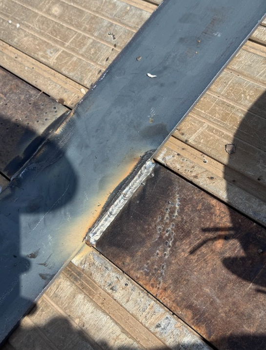 Close-up of a roof seam with dark flashing, worn shingles, and a visible gap at the edge.