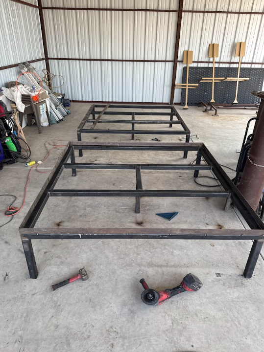Black metal frame structure in a workshop, with tools on the concrete floor.