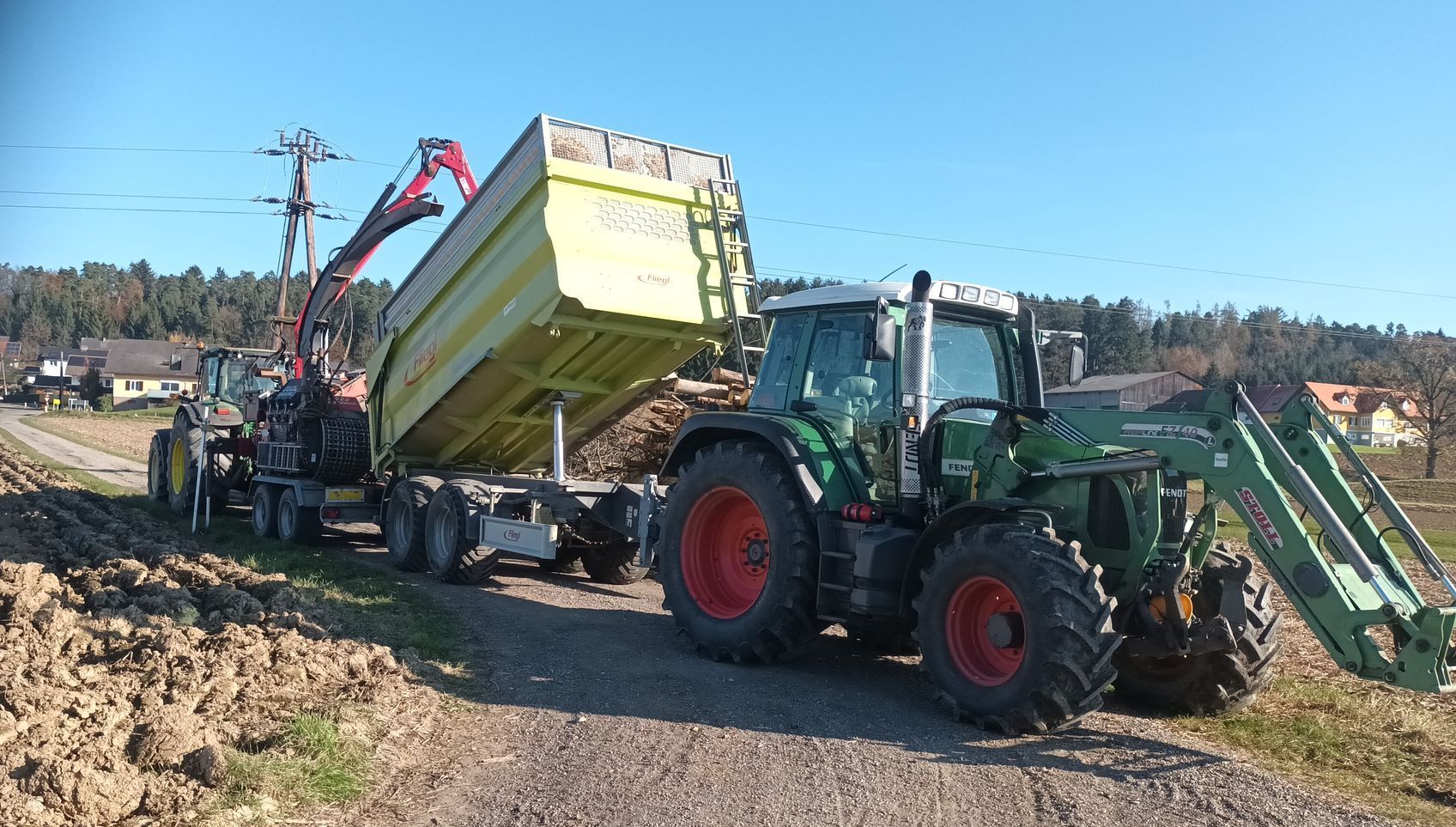 Ein Traktor zieht einen Anhänger mit einem daran befestigten Kran.