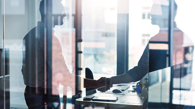 two people shaking hands in reflection of window