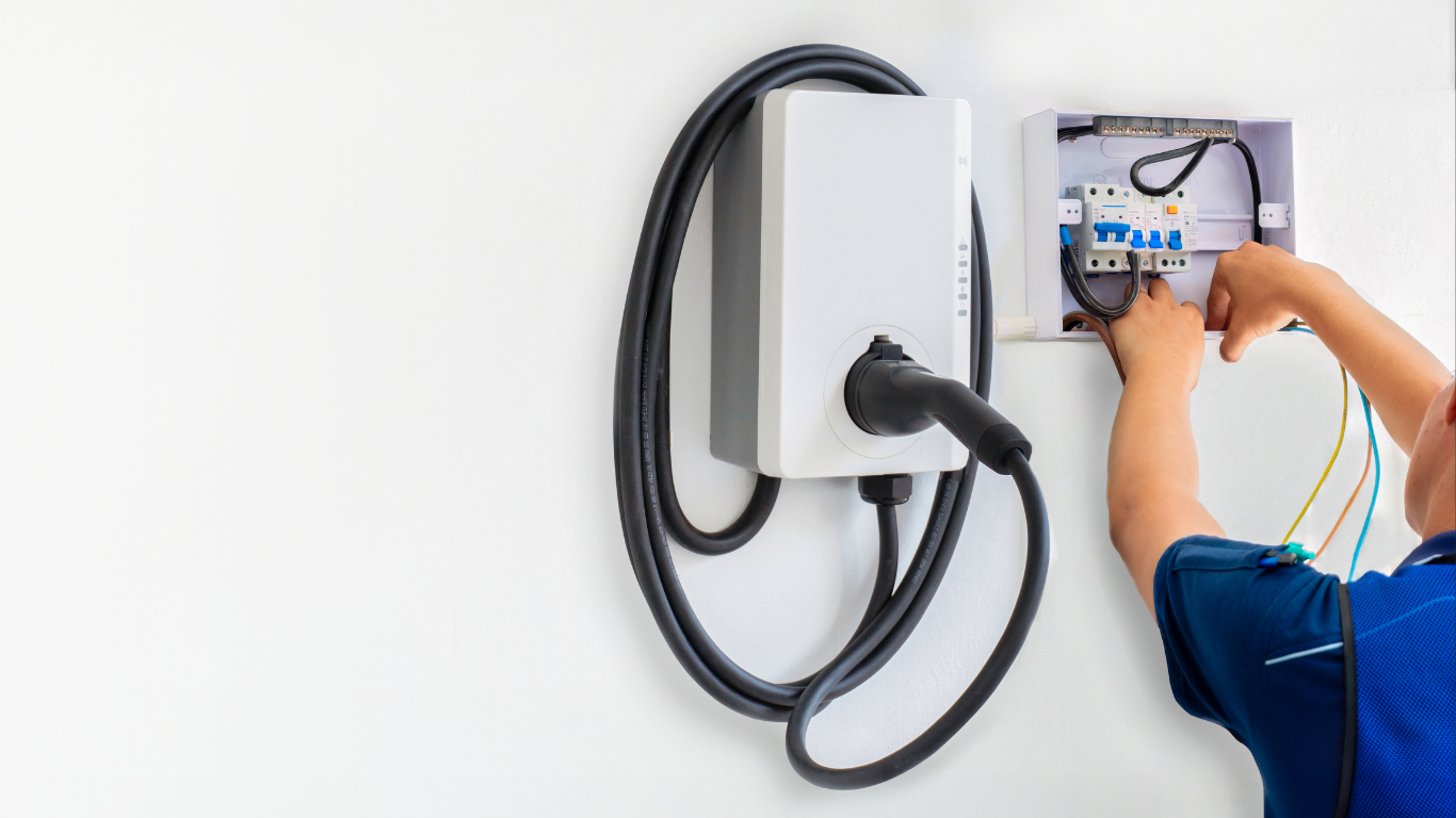 Technician wiring a wall-mounted EV charger with cables and tools