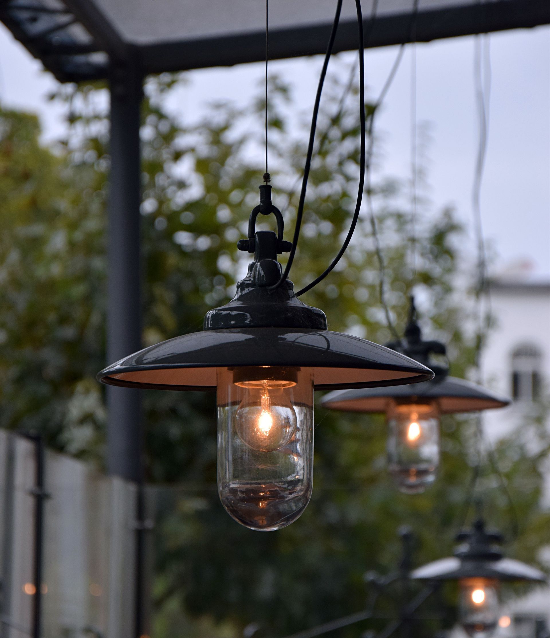 Black metal hanging lanterns glowing softly under a covered outdoor patio.