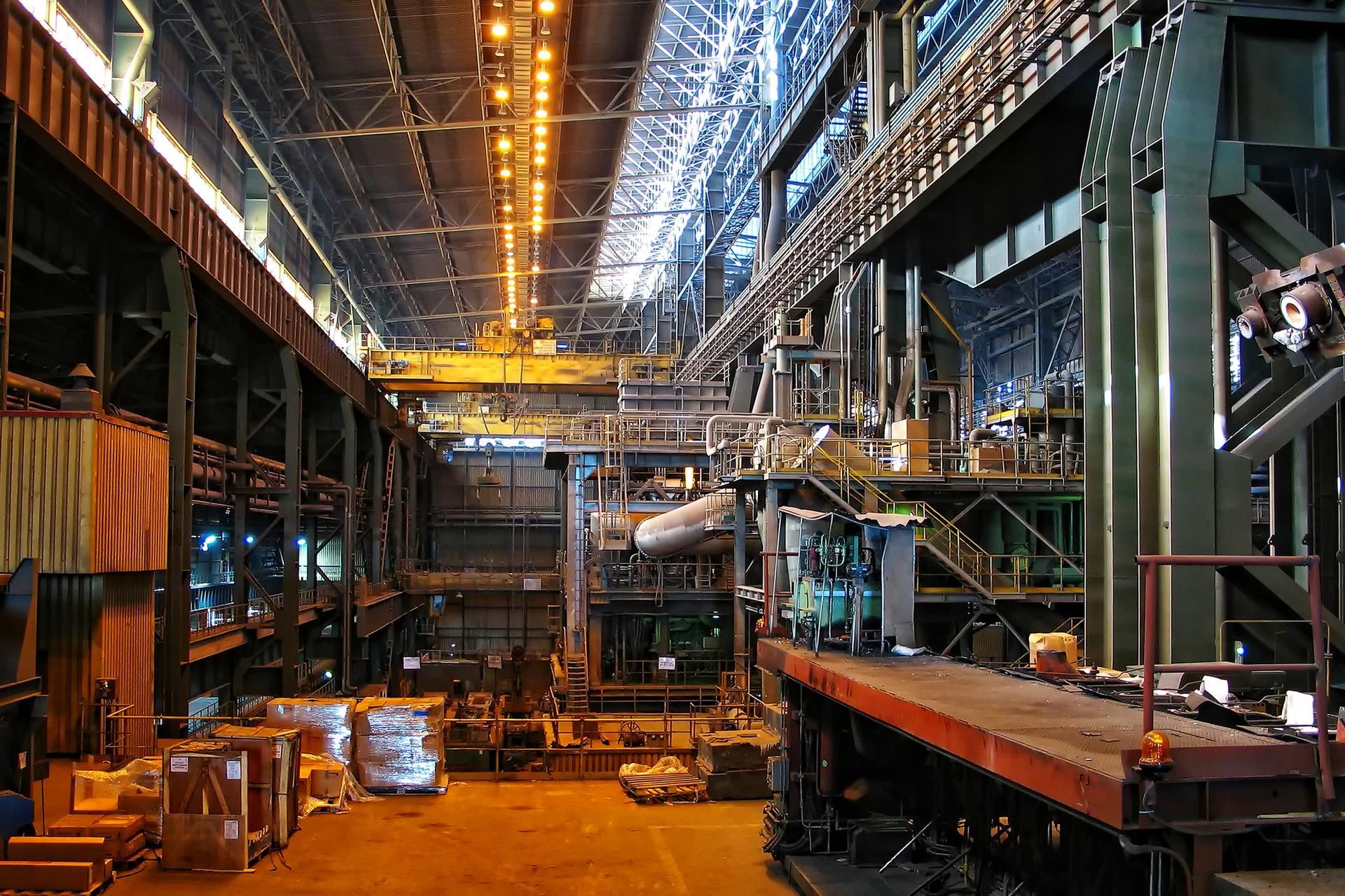 Large industrial factory interior with machinery, gantries, and overhead crane.