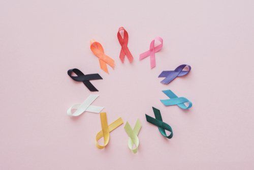 Colored awareness ribbons arranged in a circle on a pink background